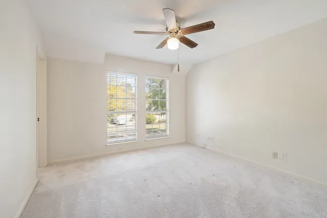 an empty room with windows and ceiling fan