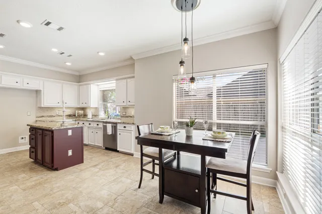a room with stainless steel appliances kitchen island granite countertop a table chairs in it and wooden floors