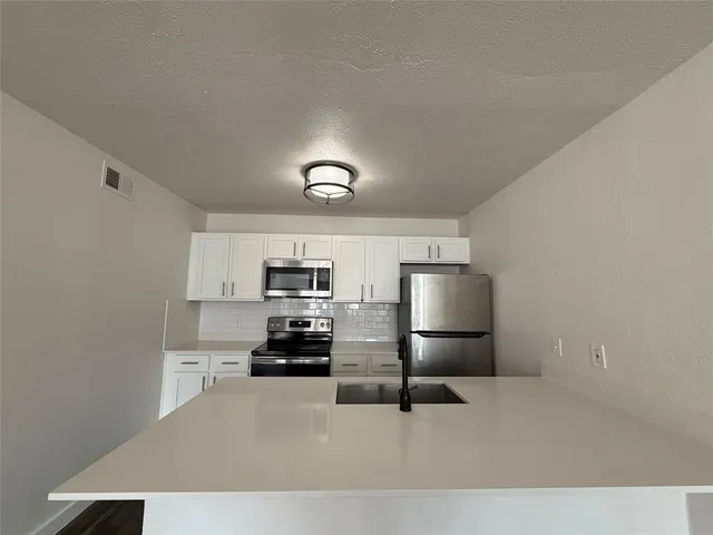 a living room with stainless steel appliances furniture a rug and a window