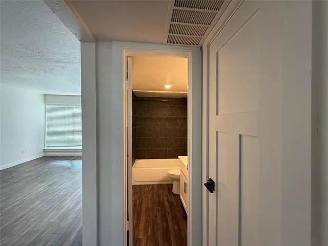 a view of a hallway with wooden floor and a bathroom