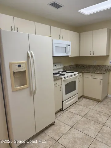 a white refrigerator freezer and a stove sitting inside of a kitchen