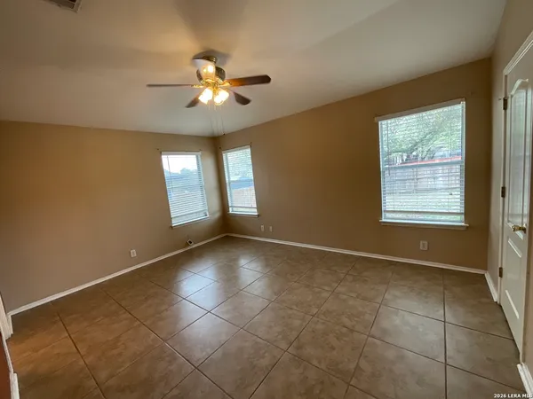 a view of an empty room with window and chandelier fan