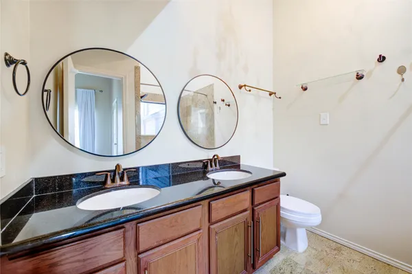 a bathroom with a granite countertop toilet a sink and a mirror