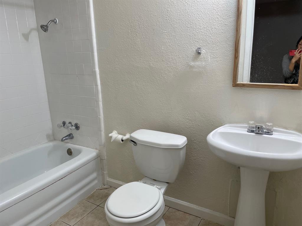 102 Roma Drive Garland, TX 75041 - Photo 7 of 9 Bathroom featuring a white porcelain pedestal sink, white toilet, and a bathtub with white subway tile surround