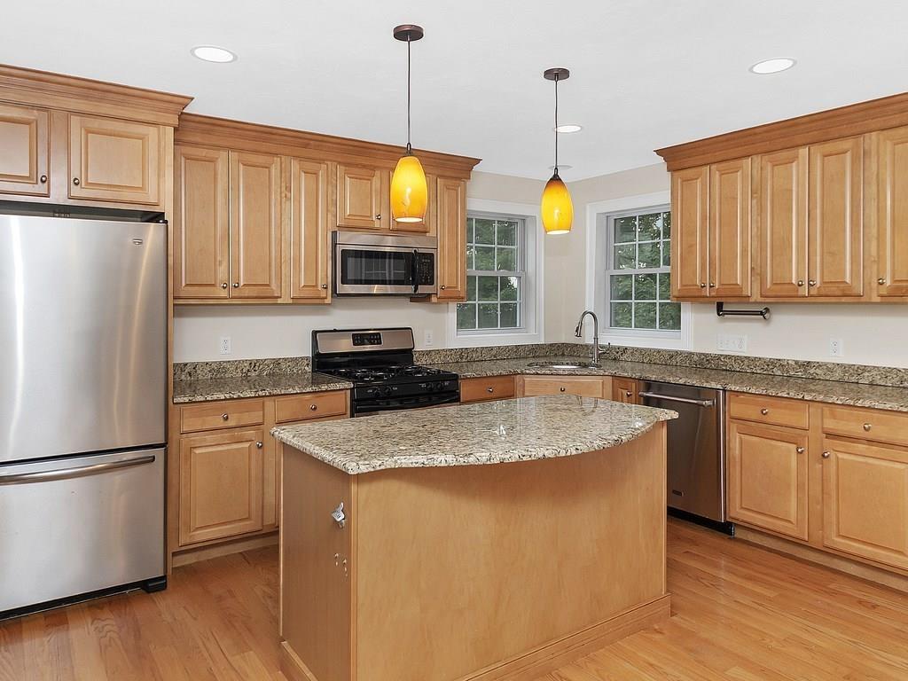 179 Florence Road Waltham, MA 02453 - Photo 3 of 37 a kitchen with stainless steel appliances granite countertop a refrigerator a sink dishwasher a oven a dining table and chairs with wooden floor
