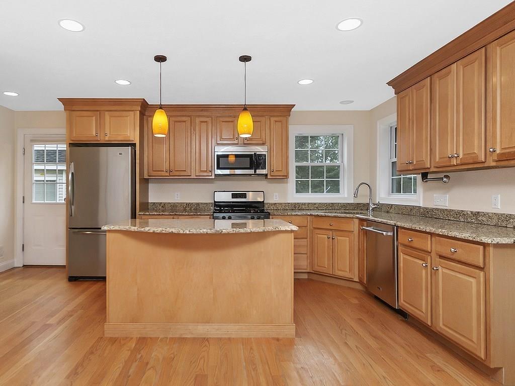 179 Florence Road Waltham, MA 02453 - Photo 4 of 37 a kitchen with stainless steel appliances granite countertop a stove a sink a refrigerator and white cabinets with wooden floor