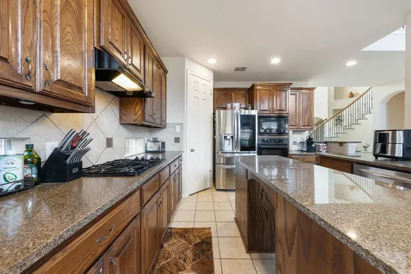 a kitchen with stainless steel appliances granite countertop a sink a stove and a wooden cabinets