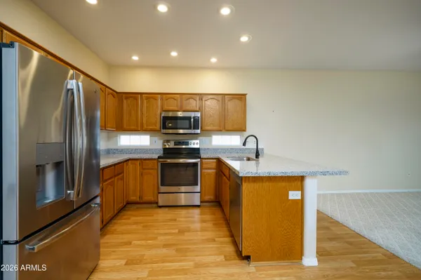 a kitchen with stainless steel appliances granite countertop a refrigerator a sink a stove and island