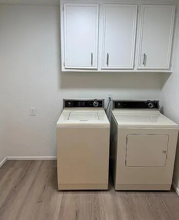 a utility room with wooden floor washer dryer and cabinets