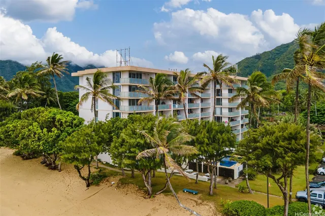 a front view of a multi story residential apartment building with yard and seating space