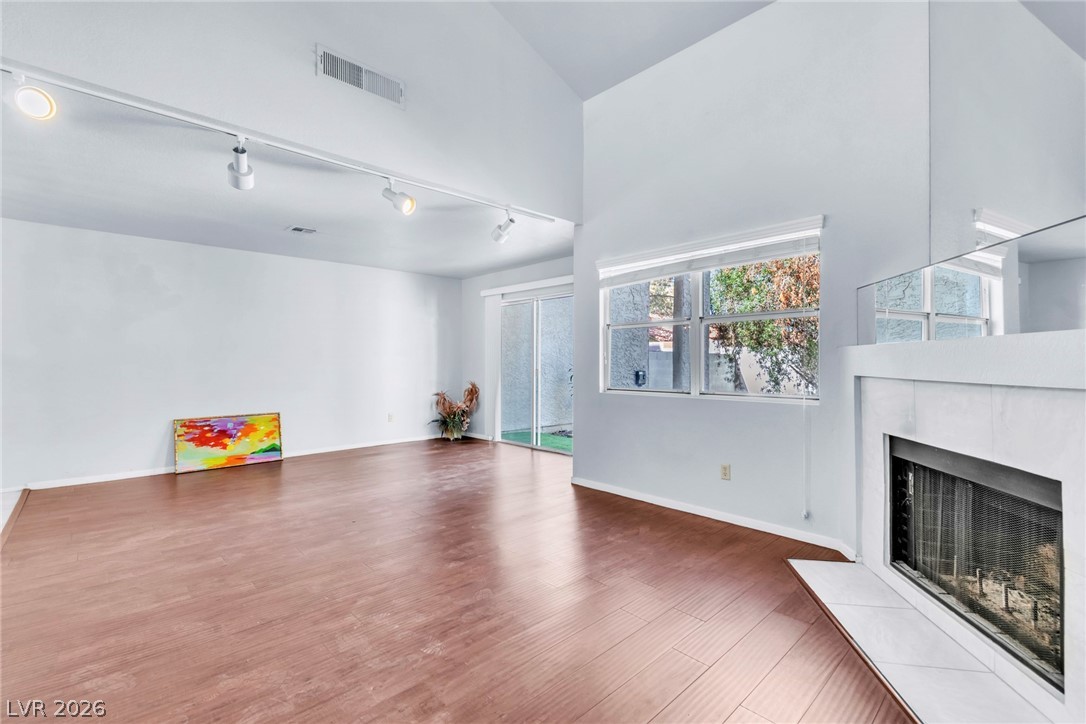 6250 West Flamingo Road, Unit 98 Las Vegas, NV 89103 - Photo 15 of 40 Unfurnished living room with wood finished floors, a tile fireplace, baseboards, and visible vents