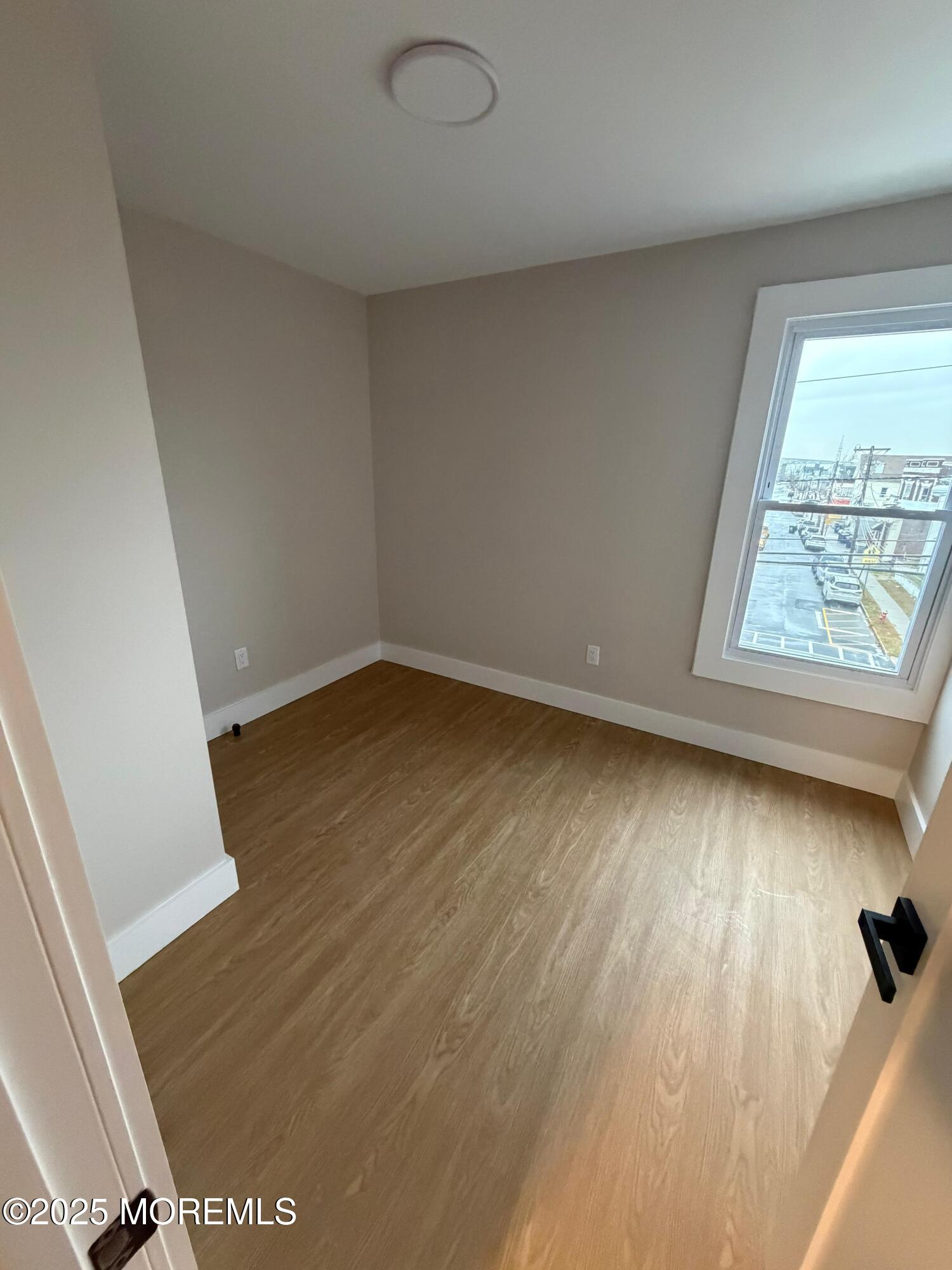 142 State Street, Unit 1 Perth Amboy, NJ 08861 - Photo 4 of 6 an empty room with wooden floor and windows