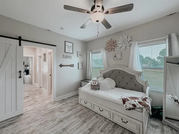 a bedroom with a bed dresser and wooden floor