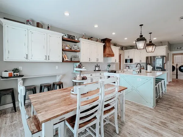 a kitchen with stainless steel appliances kitchen island granite countertop a table chairs and a refrigerator