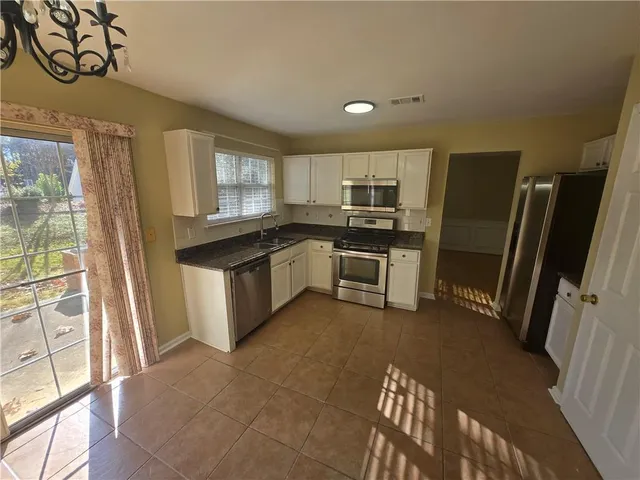 a kitchen with granite countertop a stove sink and microwave