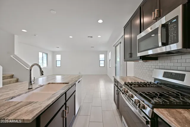 a kitchen with stainless steel appliances granite countertop refrigerator sink and microwave