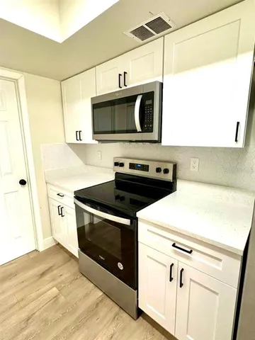 a kitchen with stainless steel appliances a stove a microwave and a shower