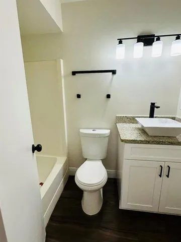 a bathroom with a granite countertop toilet sink and mirror