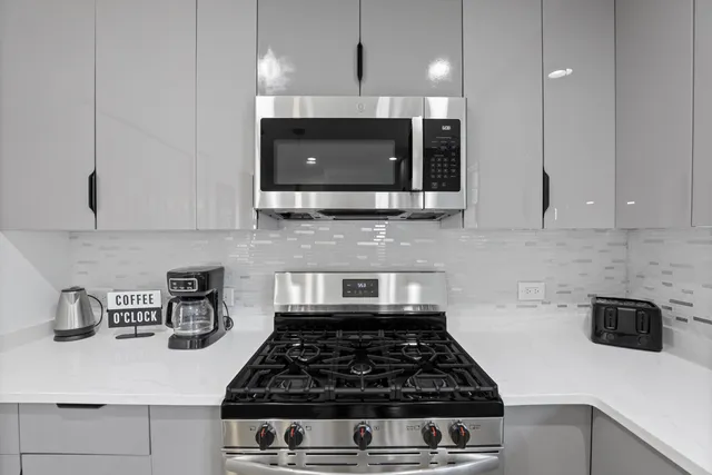 a kitchen with kitchen island granite countertop a stove a sink a microwave and cabinets