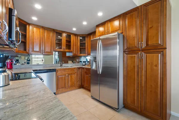 a kitchen with stainless steel appliances granite countertop a refrigerator a sink and blue cabinets