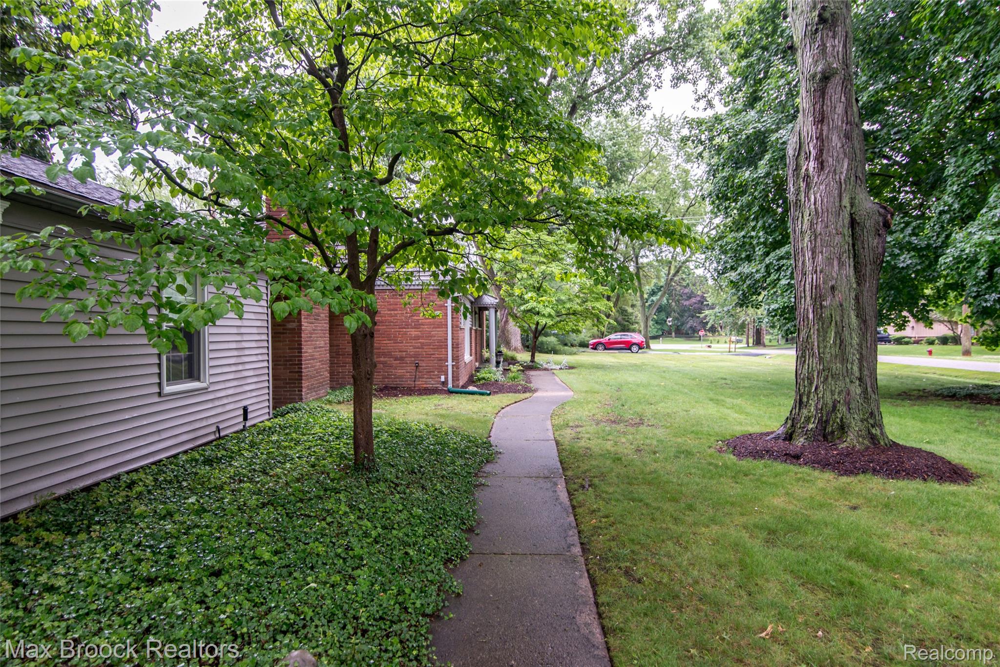 6799 East Dartmoor Road West Bloomfield, MI 48322 - Photo 35 of 36 Expansive front yard featuring a concrete pathway, mature trees, manicured lawn, and lush ground cover