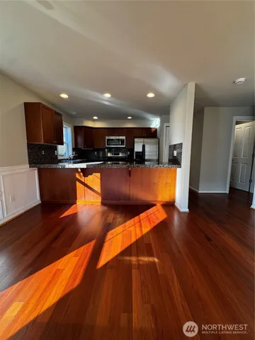 a view of a kitchen with kitchen island a counter space a sink and wooden floor
