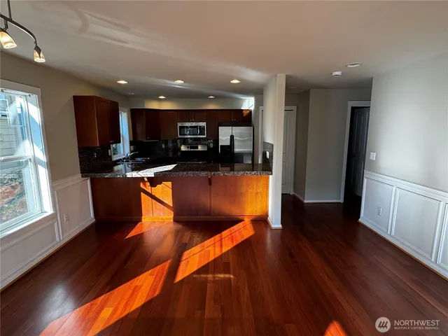 a kitchen with stainless steel appliances granite countertop wooden floors a stove and a sink