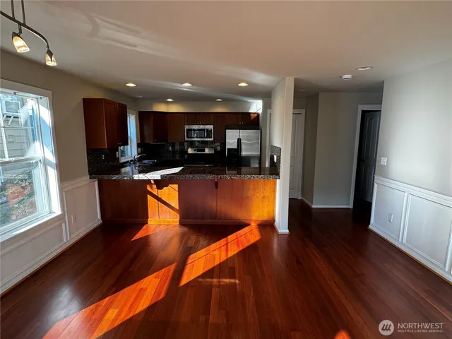 a view of a kitchen with kitchen island a counter top space a sink a refrigerator and a view of living room