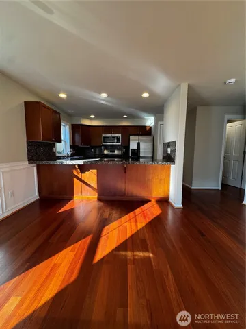 a kitchen with stainless steel appliances wooden floors and large window
