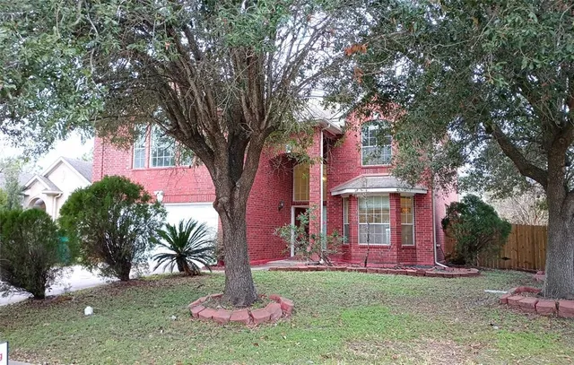 a front view of a house with a garden and tree