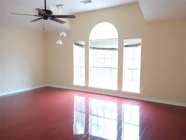 an empty room with a window and a ceiling fan