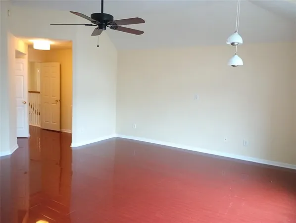 a view of a room with wooden floor and a ceiling fan