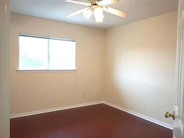 an empty room with a window and a fan