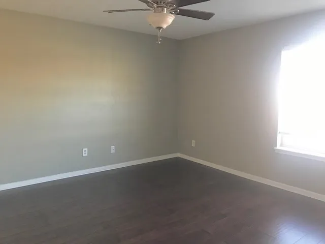 an empty room with a window and a fan
