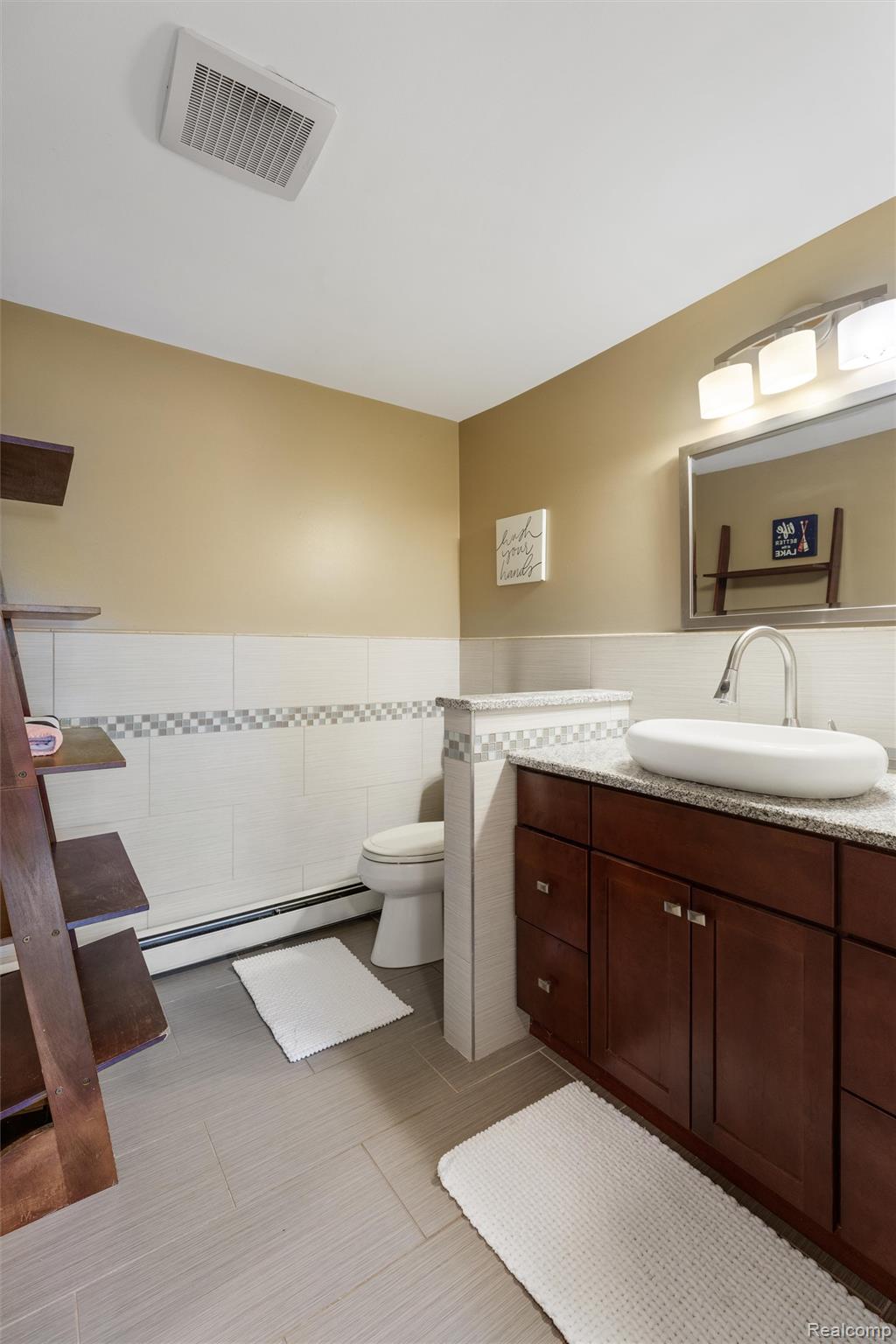 415 Leon Road Walled Lake, MI 48390 - Photo 11 of 47 Full bathroom featuring a dark wood vanity with a vessel sink, a granite-finish countertop, and a vanity mirror with overhead lighting