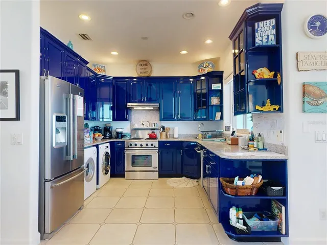 a kitchen with granite countertop stainless steel appliances a stove refrigerator and a refrigerator