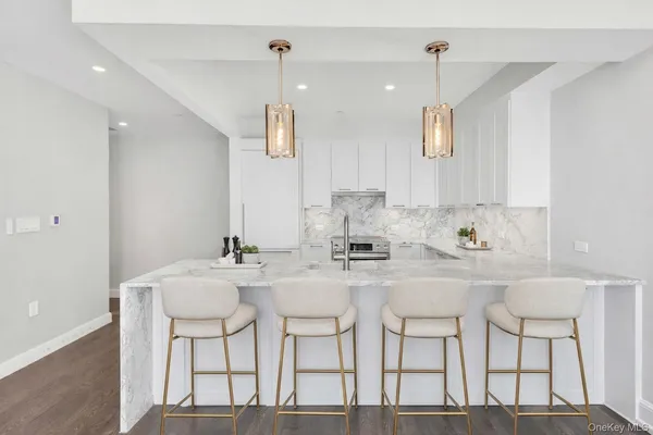 a kitchen with stainless steel appliances kitchen island granite countertop a dining table chairs and white cabinets
