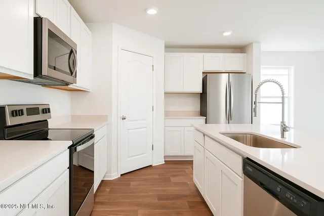 a view of a kitchen with wooden floor and electronic appliances