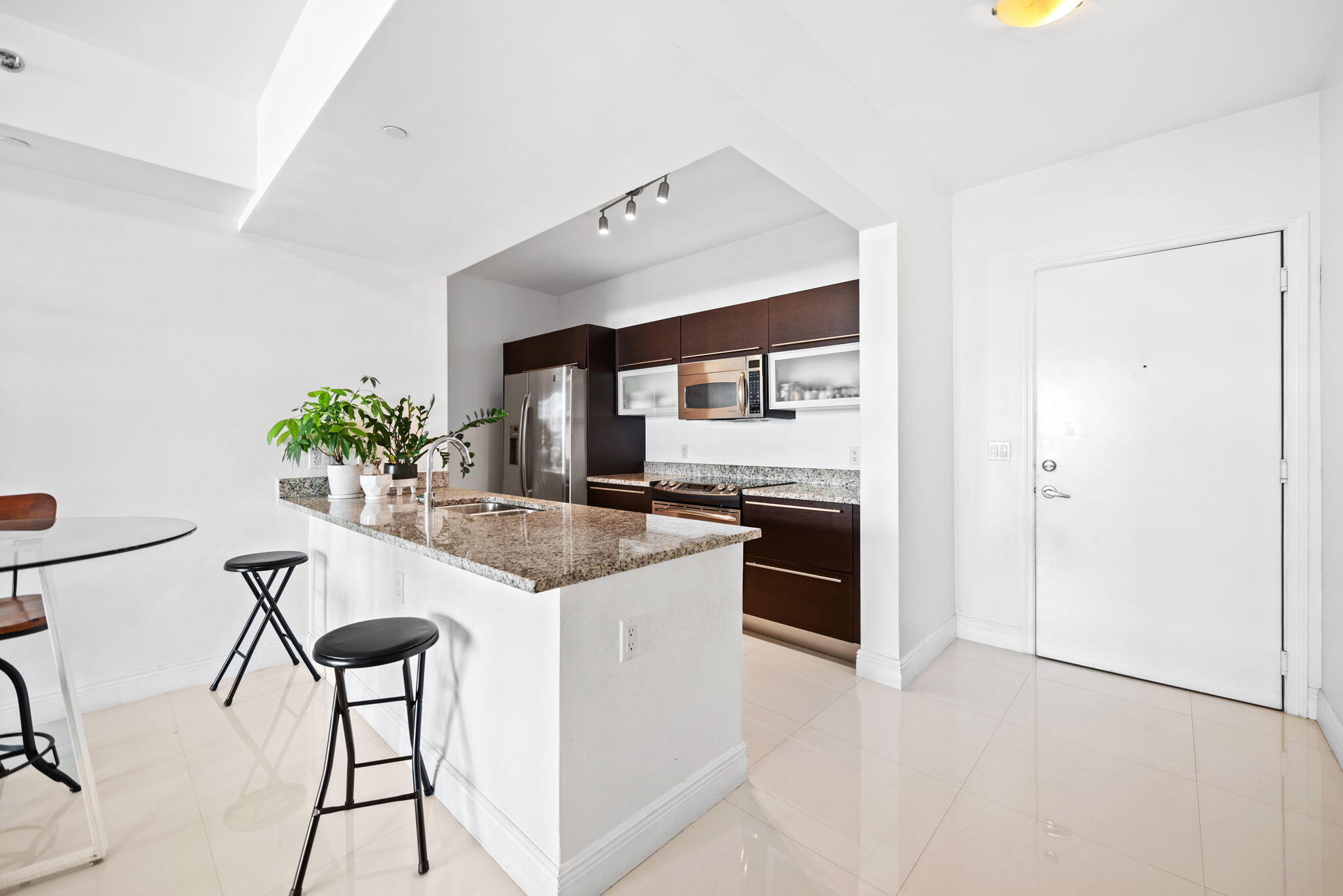 951 Brickell Avenue, Unit 400 Miami, FL 33131 - Photo 6 of 40 a kitchen with stainless steel appliances kitchen island a table and chairs in it