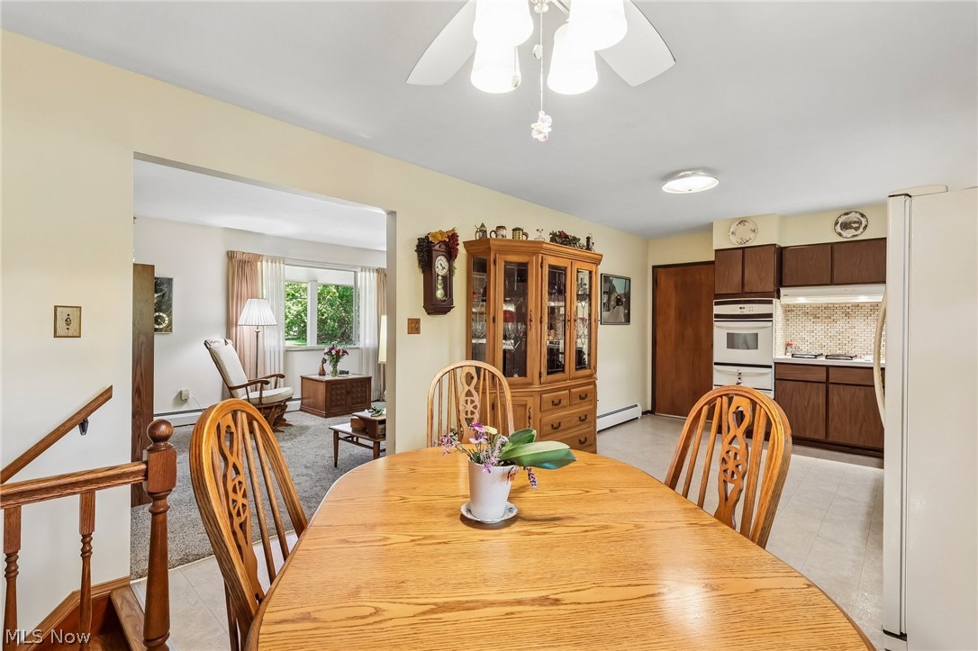 2428 Antioch Road Perry, OH 44081 - Photo 21 of 46 Dining area with overhead ceiling fan, showcasing a kitchen with wood-finish cabinetry, built-in oven, and a tiled backsplash