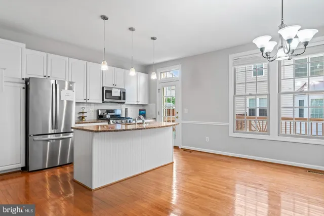 a kitchen with stainless steel appliances granite countertop a refrigerator a stove a sink dishwasher and a refrigerator with wooden floor