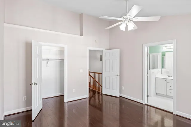 an empty room with wooden floor closet and windows