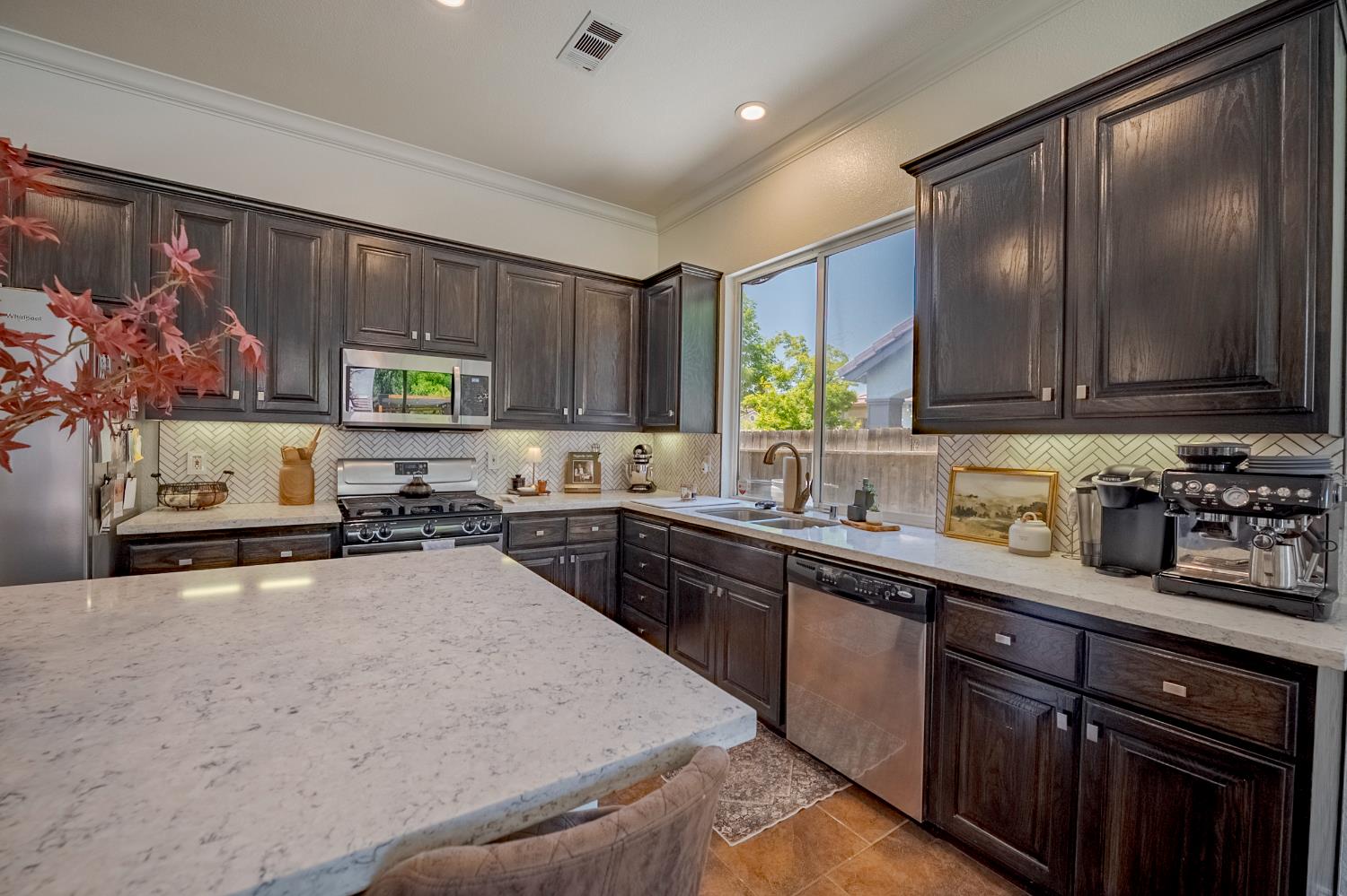 1833 La Quinta Court Merced, CA 95340 - Photo 24 of 55 a kitchen with kitchen island granite countertop a sink cabinets stainless steel appliances and a window