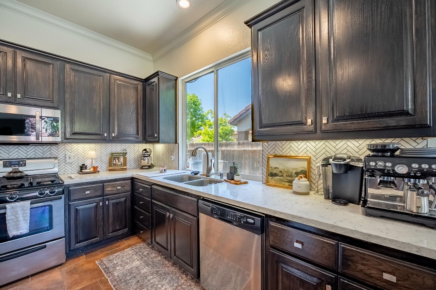 1833 La Quinta Court Merced, CA 95340 - Photo 25 of 55 a kitchen with a sink a stove cabinets and wooden floor