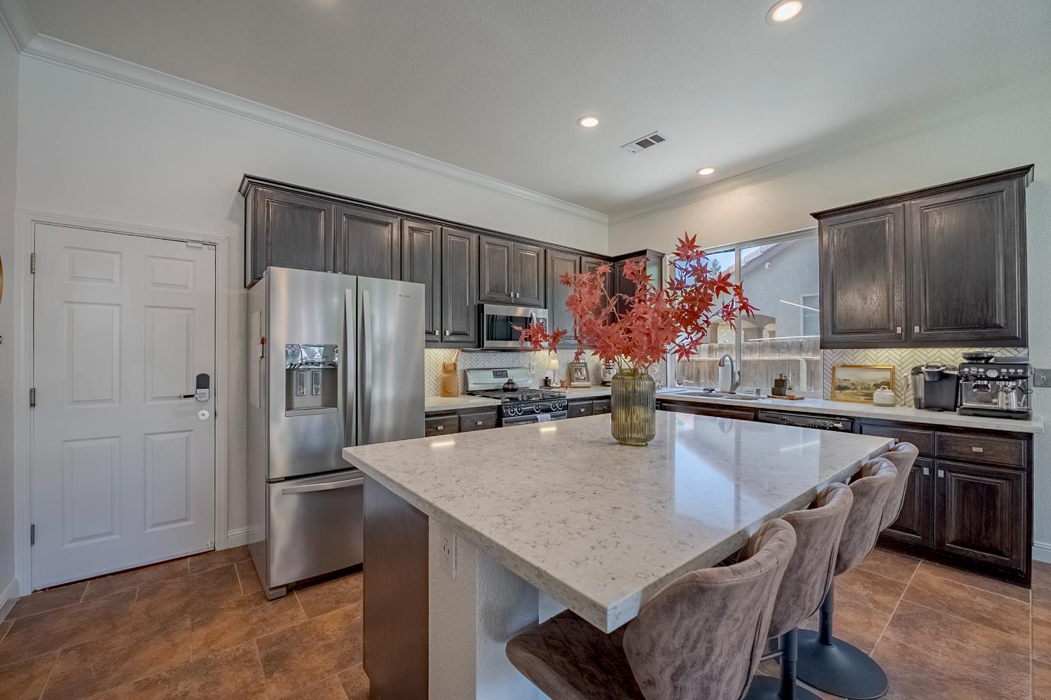 1833 La Quinta Court Merced, CA 95340 - Photo 26 of 55 a kitchen with stainless steel appliances a microwave a stove a refrigerator a sink a dining table and chairs