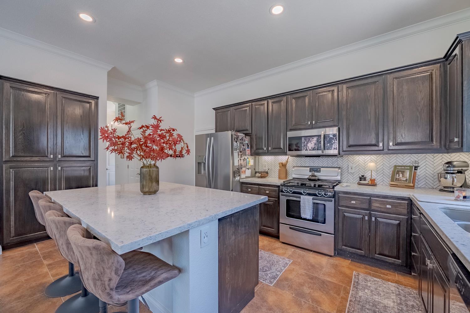 1833 La Quinta Court Merced, CA 95340 - Photo 27 of 55 a kitchen with stainless steel appliances granite countertop a stove refrigerator a sink dishwasher with a dining table and chairs