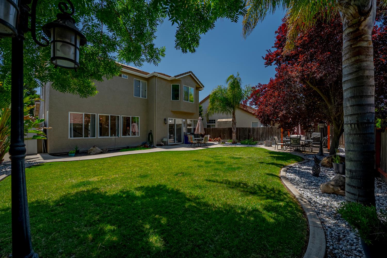 1833 La Quinta Court Merced, CA 95340 - Photo 54 of 55 a backyard of a house with table and chairs plants and a large tree