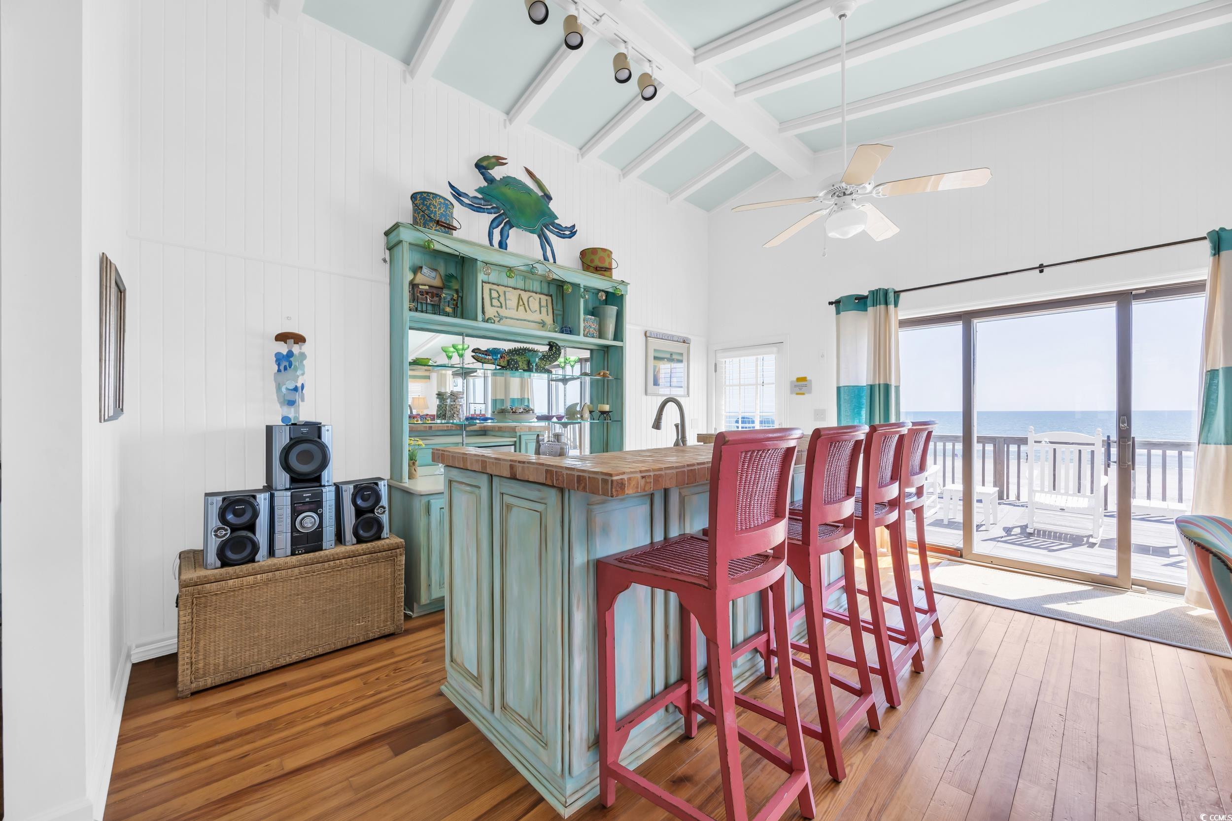 471 Norris Drive Pawleys Island, SC 29585 - Photo 13 of 40 Kitchen with green cabinetry, butcher block counters, a kitchen bar, a towering ceiling, and light wood-type flooring
