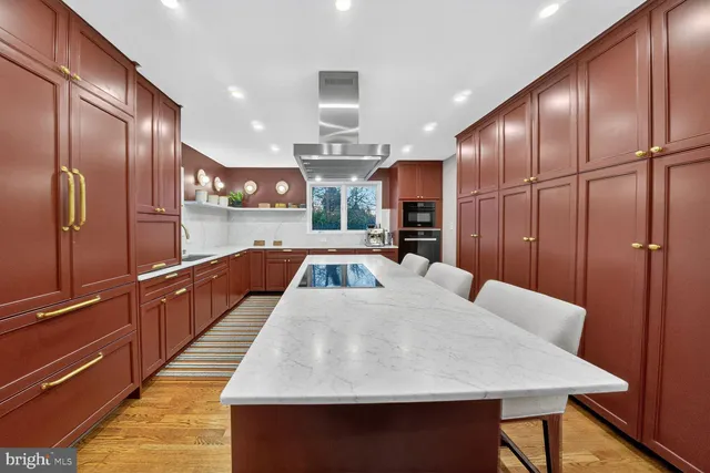 a large kitchen with stainless steel appliances kitchen island granite countertop a table chairs in it and wooden floors