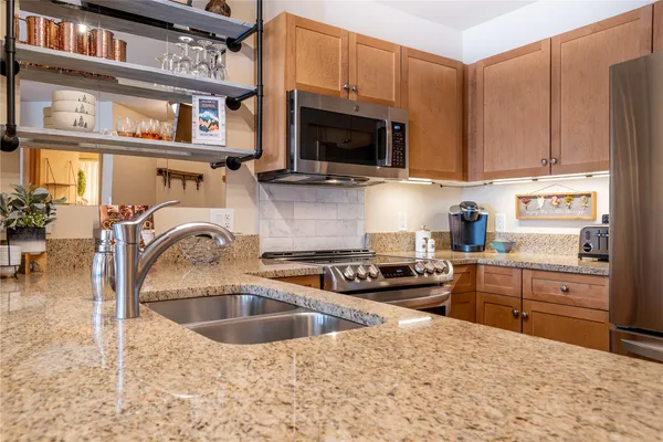 a kitchen with stainless steel appliances granite countertop a sink a stove and cabinets